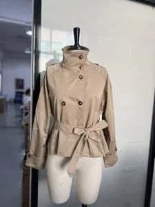 Dettaglio di un trench corto kaki con collo a lupetto e cintura in vita.