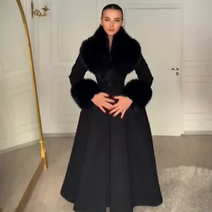 Manteau d'hiver long noir élégant avec col en fourrure amovible et jupe évasée à la taille.