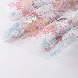 Detailed close-up showing intricate floral sequin embroidery and beadwork on white mesh fabric