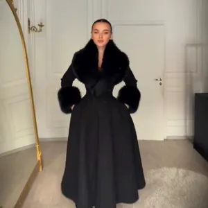 Vue détaillée d'un manteau en laine noire ajusté avec un grand col en fausse fourrure