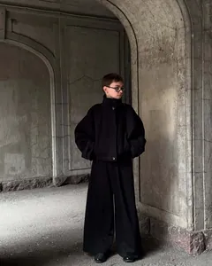 Donna elegante che indossa una giacca di lana nera con collo alto in un arco di pietra