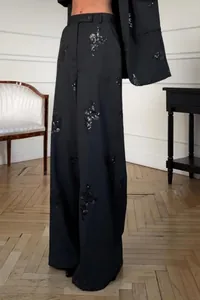 Detail view of black sequin floral embroidery on high-waist wide-leg suit trousers