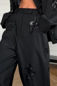 Detailed view of elegant black striped suit pants with sequin floral embroidery accents