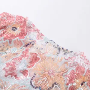 Close-up detail of heavy industry floral sequin embroidery on women's summer top fabric.