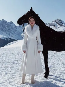 Manteau long en laine blanche avec col en fourrure amovible dans un paysage enneigé