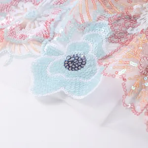 Macro detail of high-quality floral sequin embroidery on white mesh fabric for summer tops