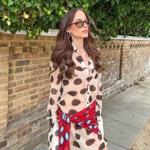 Elegant polka dot long sleeve shirt dress styled with a vibrant red patterned waist scarf