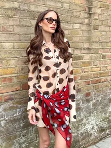 Elegant loose-fit shirt dress featuring large spot prints and a vibrant red waist scarf