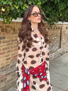 Stylish loose long-sleeved shirt dress with bold blotch print and a red waist scarf.