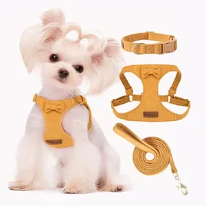 Detailed view of a mustard yellow corduroy dog harness set with a bow on a white puppy