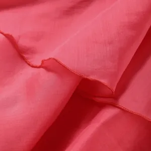 Macro detail of the red lightweight fabric and ruffled hemline of the vacation dress.