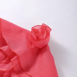 Close-up detail of a 3D fabric flower and delicate ruffled edges on a pink summer dress