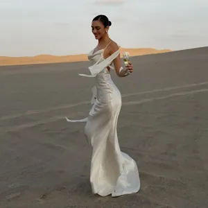 Elegantes weißes Satin-Maxikleid mit offenem Rücken, präsentiert in einer Wüstenlandschaft.