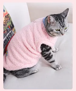 Gilet douillet en polaire rose pour chats et chiens, porté par un chat tigré sur un canapé.