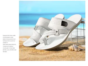 Detailaufnahme von weißen Herren-Freizeitsandalen am Sandstrand mit Meerblick