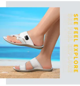 Detailansicht von weißen Herren-Sandalen am Sandstrand beim Tragen