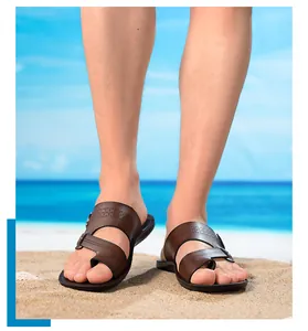 Detaillierte Ansicht brauner Leder-Sandalen für Herren an einem sonnigen Sandstrand