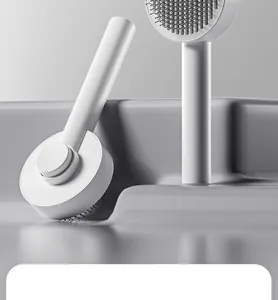 Close-up of a minimalist white press-type pet grooming needle brush on a gray background