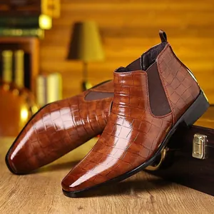 Detail van bruine heren Chelsea boots met een reliëf krokodillenleren textuur.