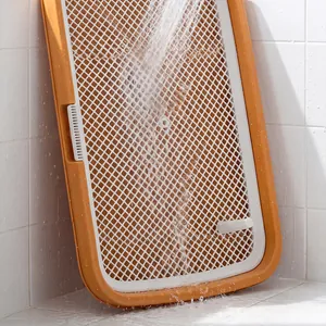 Close-up showing water rinsing a mesh pet toilet tray in a bathroom setting