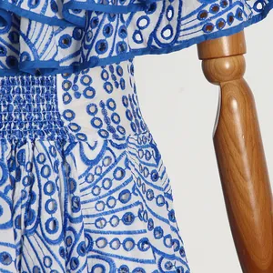 Detailaufnahme der blauen Stickerei und Lochstickerei an einem weißen Kleid mit Smoktaille.