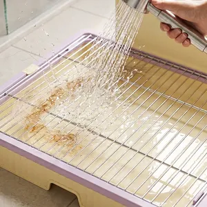 Stainless steel dog toilet pee tray with purple base being rinsed by water