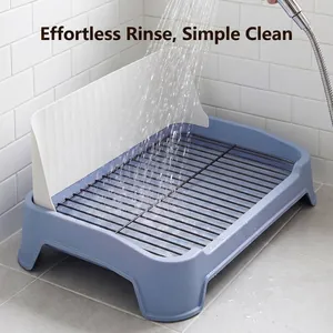 Blue dog potty tray with metal grid and splash guard being rinsed clean under water.