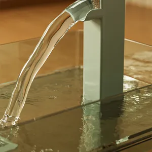 Nahaufnahme von klarem Wasser, das aus einem minzgrünen Haustierbrunnen in ein Glas fließt