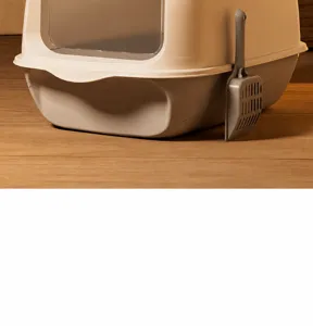 Detailansicht einer voll geschlossenen Katzentoilette mit Schaufel auf Parkett