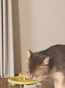 Nahaufnahme einer grauen Katze, die aus einem automatischen Trinkbrunnen für Haustiere trinkt.