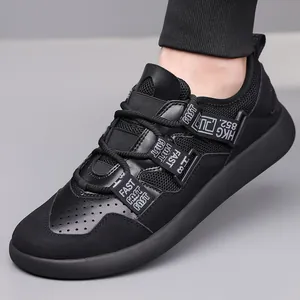 Close-up of black chunky sneakers featuring breathable mesh and decorative lettered straps