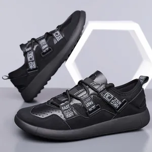 Close-up of black platform women's dad shoes with decorative logo straps and mesh detail.