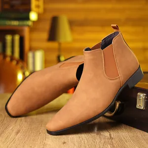 Gros plan sur des bottines Chelsea en daim marron clair sur une valise vintage haut de gamme