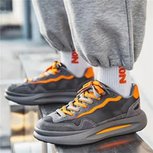 Dettaglio di sneaker casual da uomo grigie e arancioni abbinate a pantaloni sportivi grigi