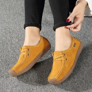 Gros plan sur des mocassins décontractés en daim jaune portés sur un tapis gris.