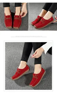 Gros plan de mocassins décontractés en daim rouge pour femmes avec surpiqûres blanches.