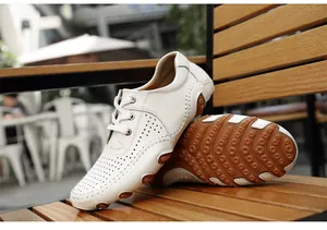 White perforated men's driving loafers with anti-slip rubber sole on wooden bench