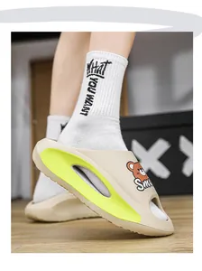 Dettaglio di ciabatte estive da uomo beige con orsetto cartoon e accenti verde brillante