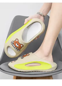 Primo piano di ciabatte beige con accenti giallo neon e design a orsetto