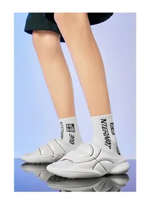 Detailed side view of white thick-soled sports slides worn with stylish athletic crew socks