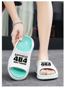 Detailansicht der weißen und mintgrünen Slipper mit dem Grafikdruck "HAPPINESS 404".