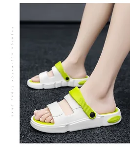 Nahaufnahme von weißen und lindgrünen Sport-Sandalen, die ein Modell auf dunklem Boden trägt