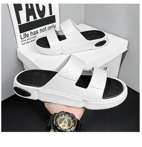 Nahaufnahme von weiß-schwarzen Slides mit dicker Sohle und Doppelriemen im Sport-Look
