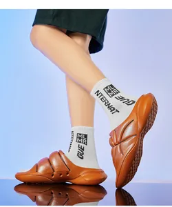 Side view of trendy orange thick-soled platform slides worn with graphic white socks