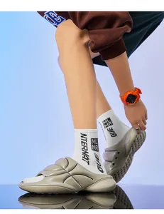 Close-up of thick-soled sporty slides worn with white crew socks and an orange watch