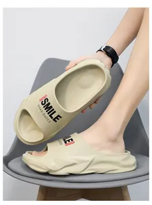 Dettaglio di ciabatte beige con suola spessa e stampa "Smile" su una sedia grigia.