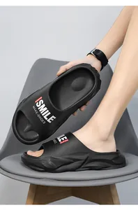 Dettaglio di ciabatte nere antiscivolo con suola spessa e logo Smile su una sedia