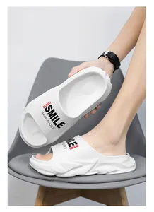 Primo piano di ciabatte bianche con zeppa, scritta SMILE e suola spessa antiscivolo