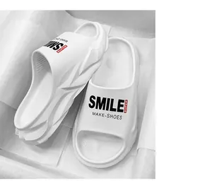 Vista ravvicinata di comode pantofole bianche a suola spessa con scritte Smile e Super