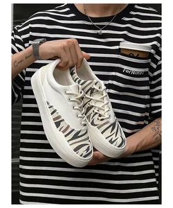 Detailansicht weißer Low-Top-Stoffschuhe mit Zebradruck vor einem gestreiften T-Shirt
